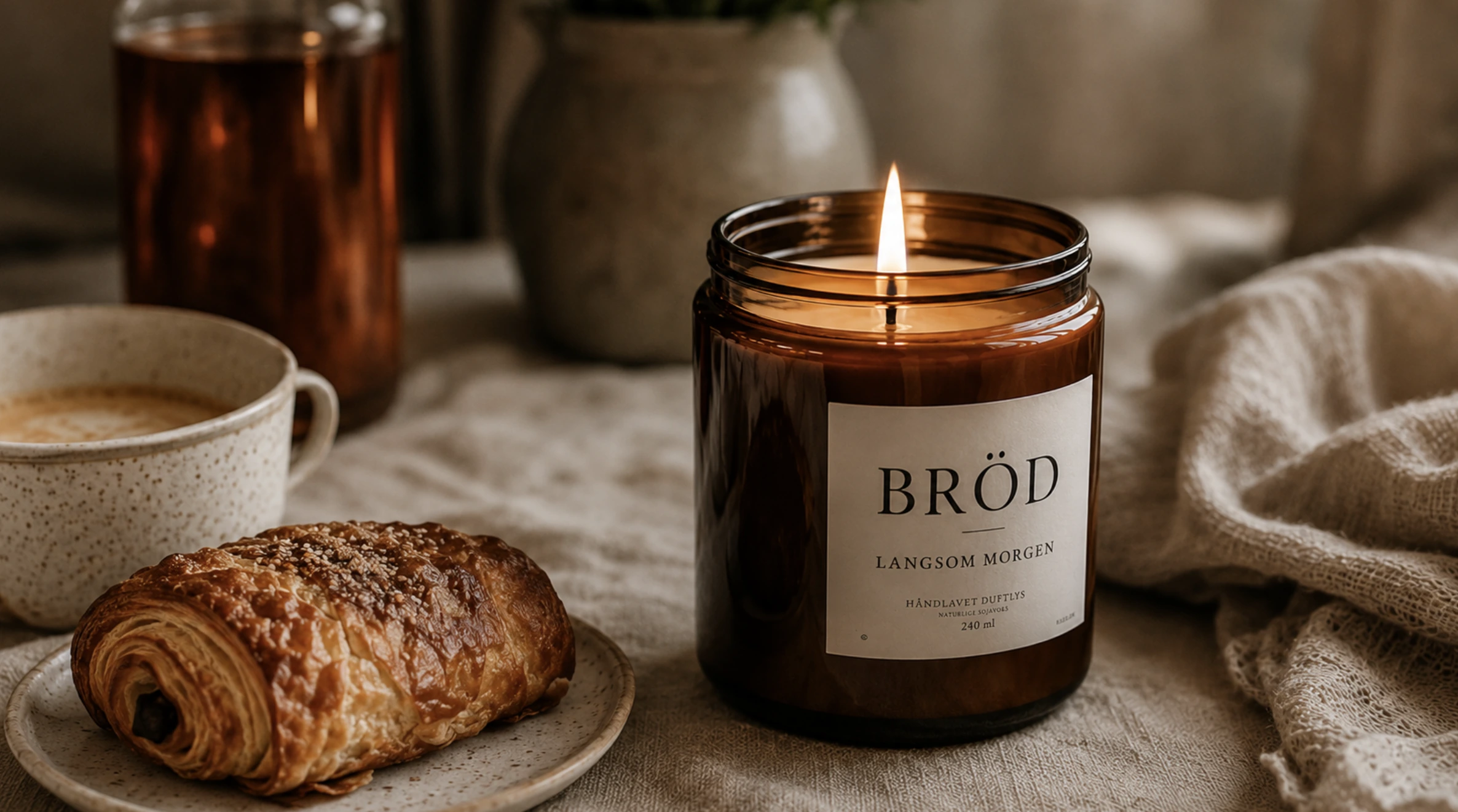 Duftlys, kaffe, pain au chocolat på et træbord